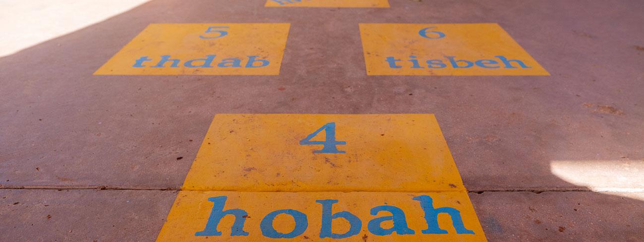 Yellow painted squares with blue numbers and words, including “4,” “5,” “6,” “home,” “happy,” and “together,” arranged on a concrete surface.