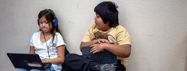 Two students working on laptop.